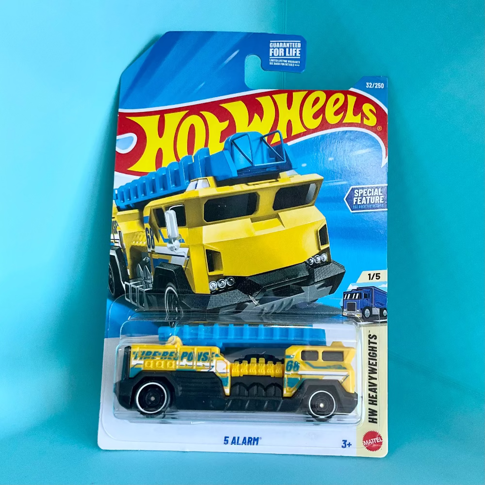 A Hot Wheels '5 Alarm' WW Heavyweights die-cast toy truck in its original blister card packaging, set against a solid light blue background.