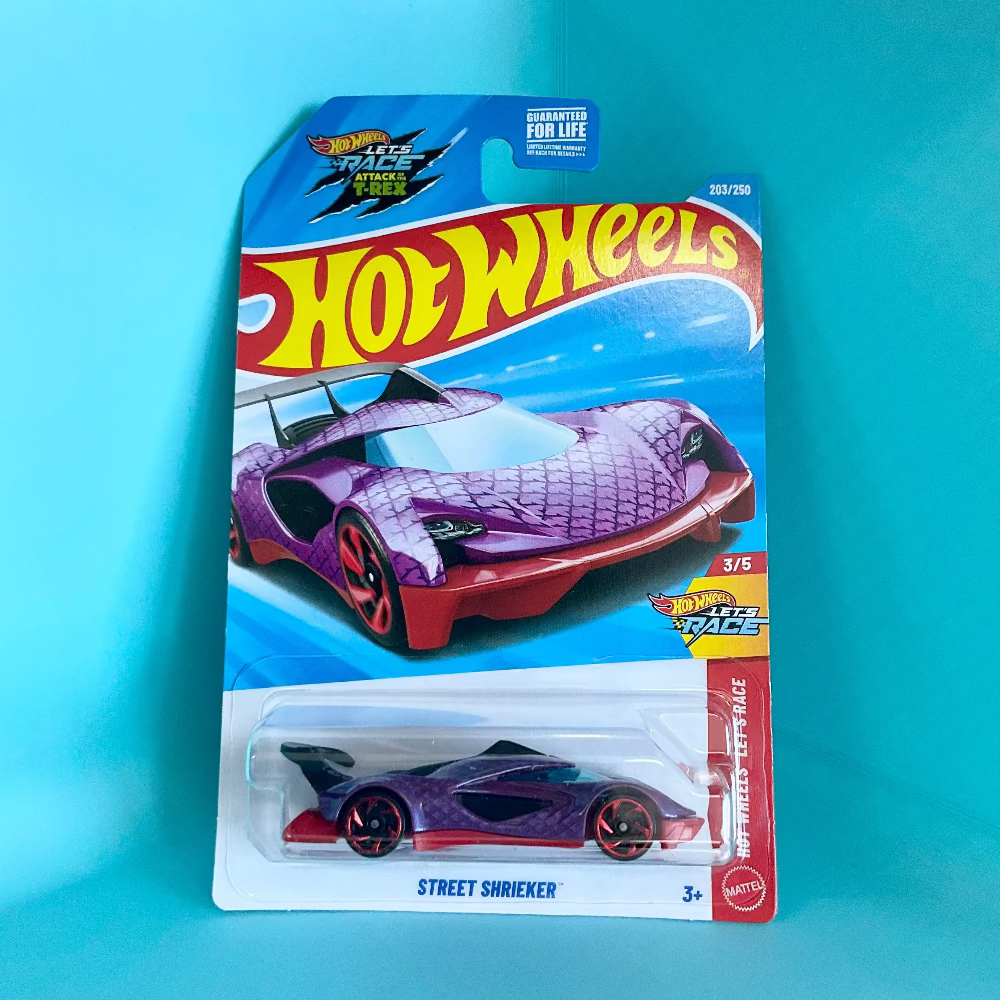 A Hot Wheels Street Shrieker toy car in its original blister card packaging, set against a bright cyan background. The card features the classic Hot Wheels logo and indicates the 'Street Shrieker' model from the 'Hot Wheels Racing' series.