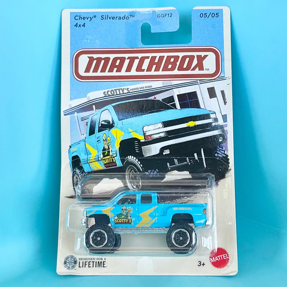 Matchbox Chevy Silverado 4x4 toy truck in its original blister card packaging, featuring a light blue truck with yellow and black graphics, set against a solid light blue background.