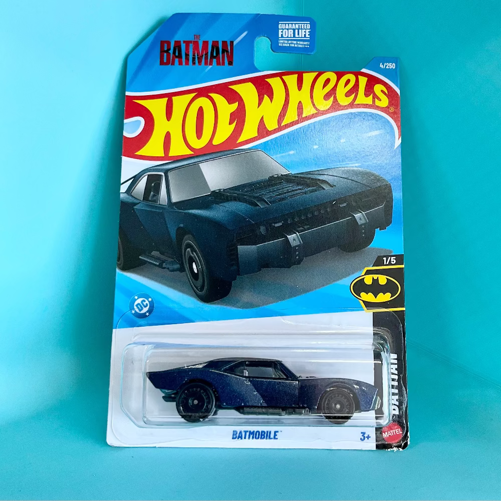 A Hot Wheels Batman Batmobile toy car in its original blister card packaging, displayed against a solid turquoise background.