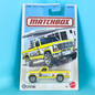 A Matchbox die-cast toy truck in its original blister card packaging, featuring a 1986 Ford F-150. The toy truck is yellow with white and black graphics, and the packaging shows a larger illustration of the same truck.