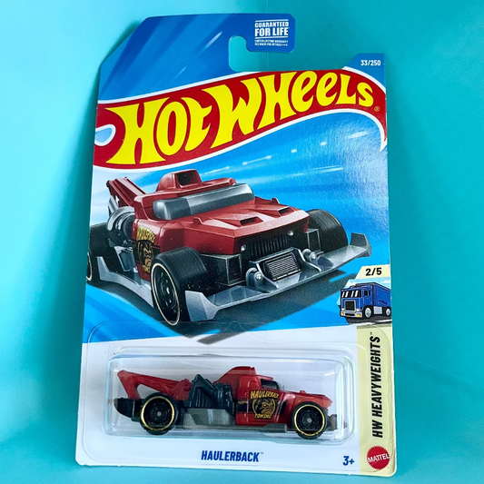 A Hot Wheels Haulerbrack toy car in its original blister card packaging, set against a bright turquoise background. The packaging features the classic red and yellow Hot Wheels logo and displays the red and black toy car inside the clear plastic bubble.