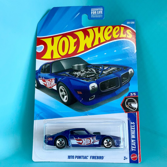 A Hot Wheels Team Wheels 1/5 scale die-cast model car of a 1970 Pontiac Firebird, shown in its original blue and white blister card packaging against a bright cyan background.