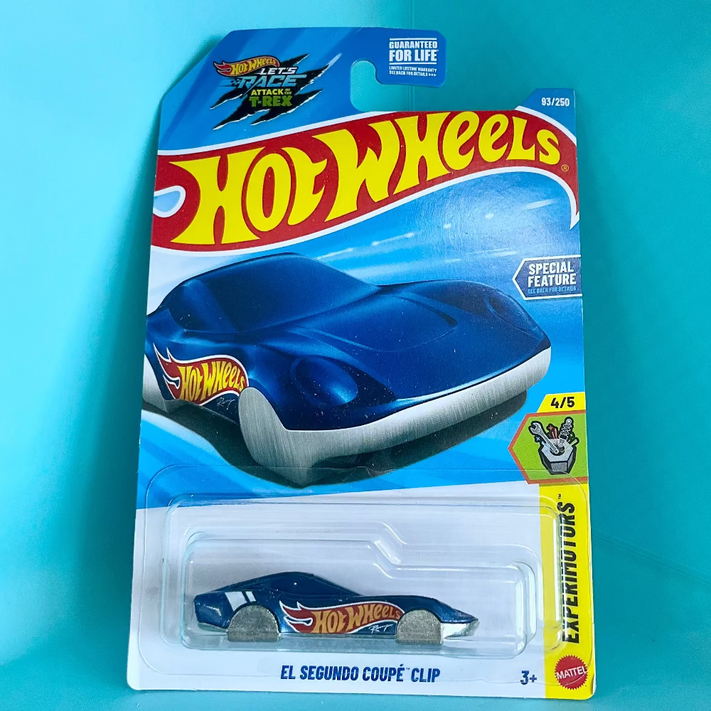 A Hot Wheels Experiments die-cast toy car in its original blister card packaging, displayed against a solid turquoise background. The packaging features the classic Hot Wheels logo and depicts a blue car on the card, while the actual toy car inside the clear plastic bubble is also blue with yellow and red flame decals.